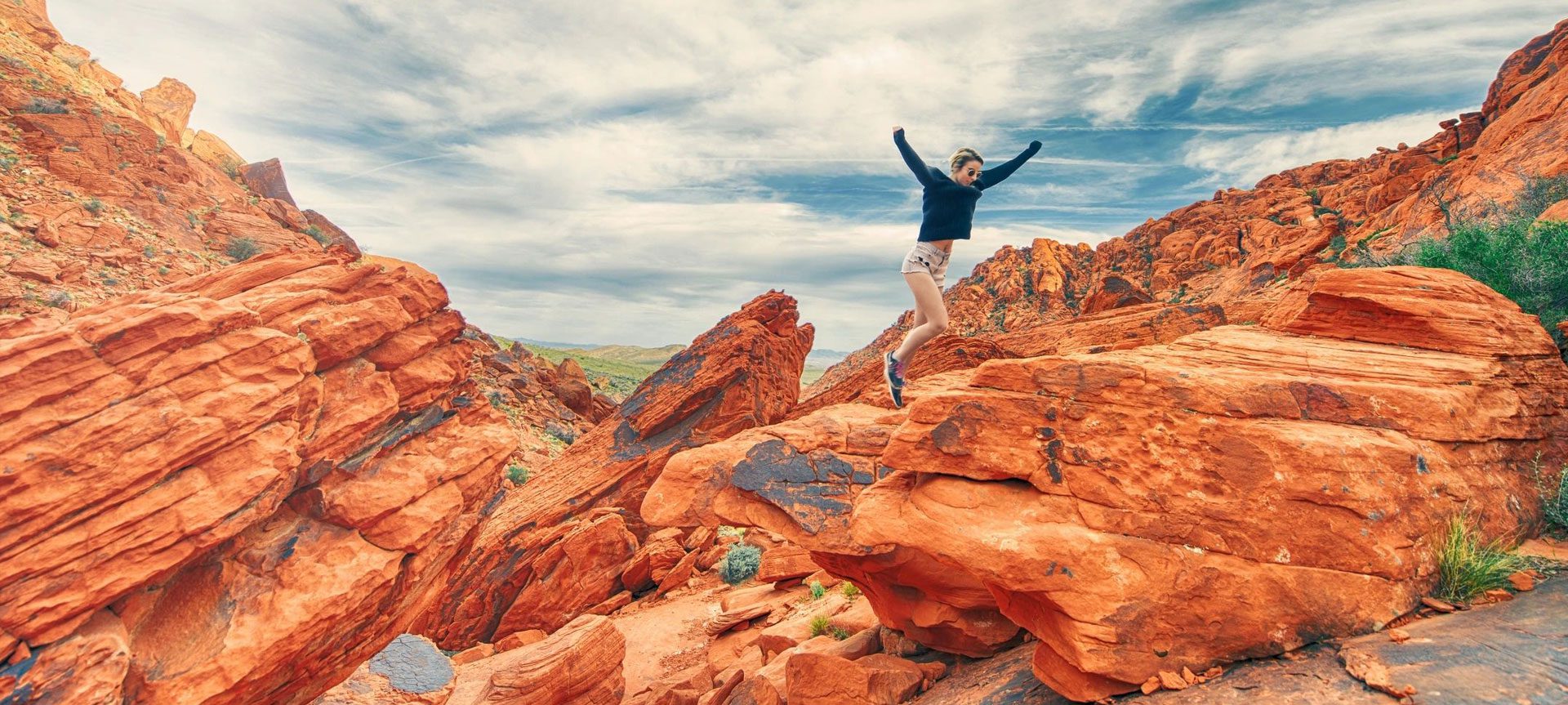 A person jumping in the air on top of rocks.